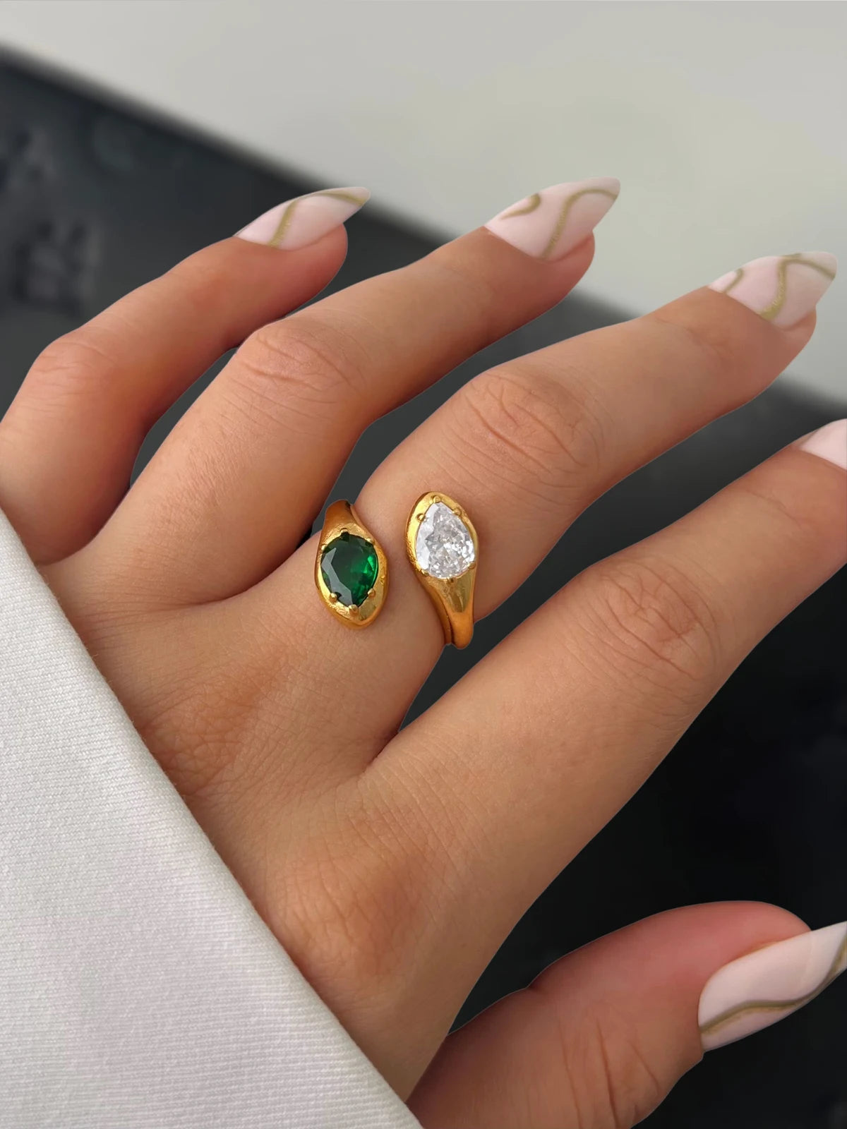 Alexandra Ring – Close‑Up Detail-Gold ring with emerald and diamond on a hand with light nail polish.