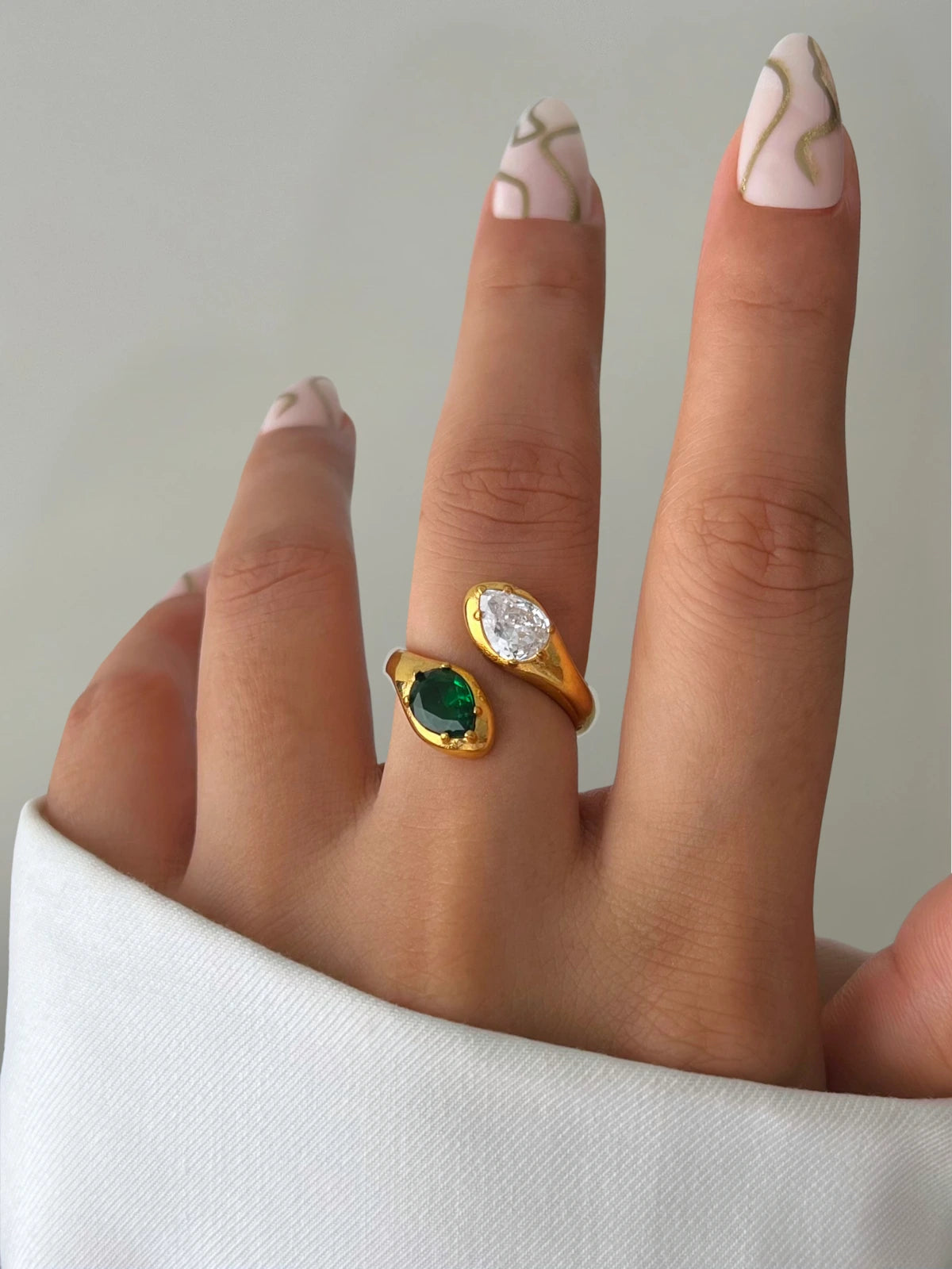 Alexandra Ring styled in everyday look — 18K gold‑plated stainless steel by Shine With Me, versatile open‑ring for all occasions-Gold ring with green gemstone on a finger against a neutral background