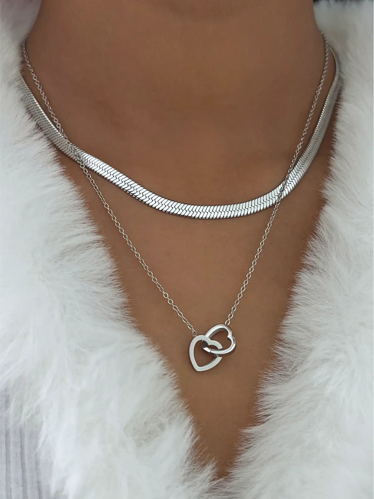 All My Love Necklace – On Model Styled Shot-Silver necklace with a heart-shaped pendant on a white fur background