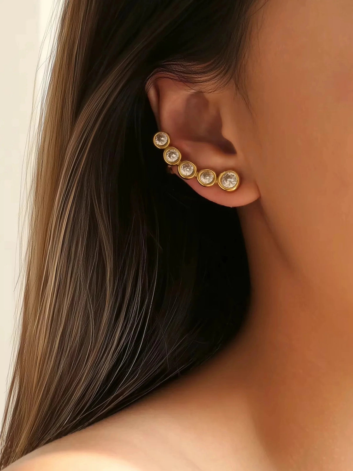 Ana Earring & Cuff worn on ear — 18K gold-plated stainless steel with cubic zirconia by Shine With Me, styled look-Close-up of an ear wearing a gold earring with clear stones.