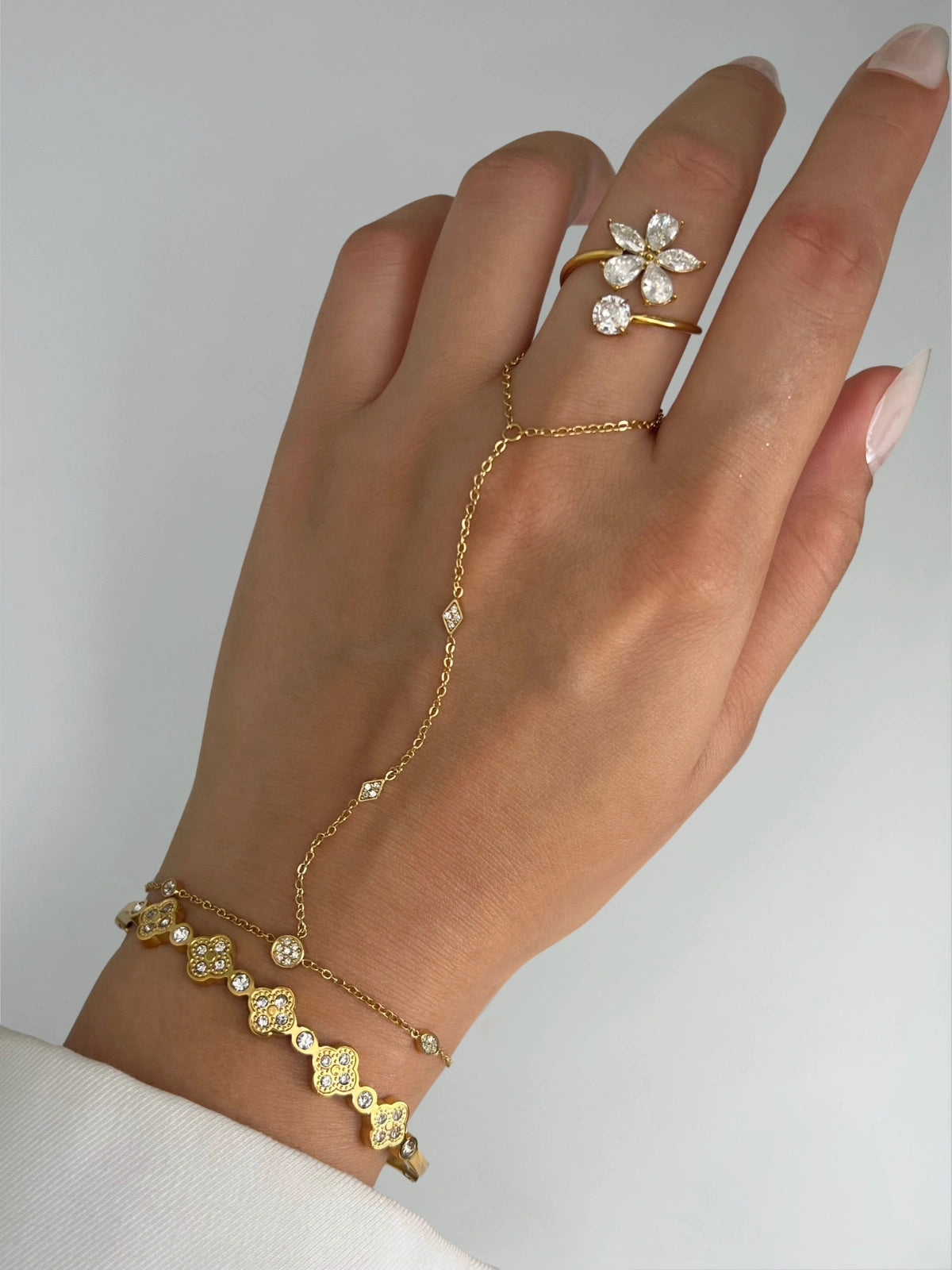 Arabella Hand Harness – Hand wearing a gold bracelet and ring with diamond accents on a neutral background