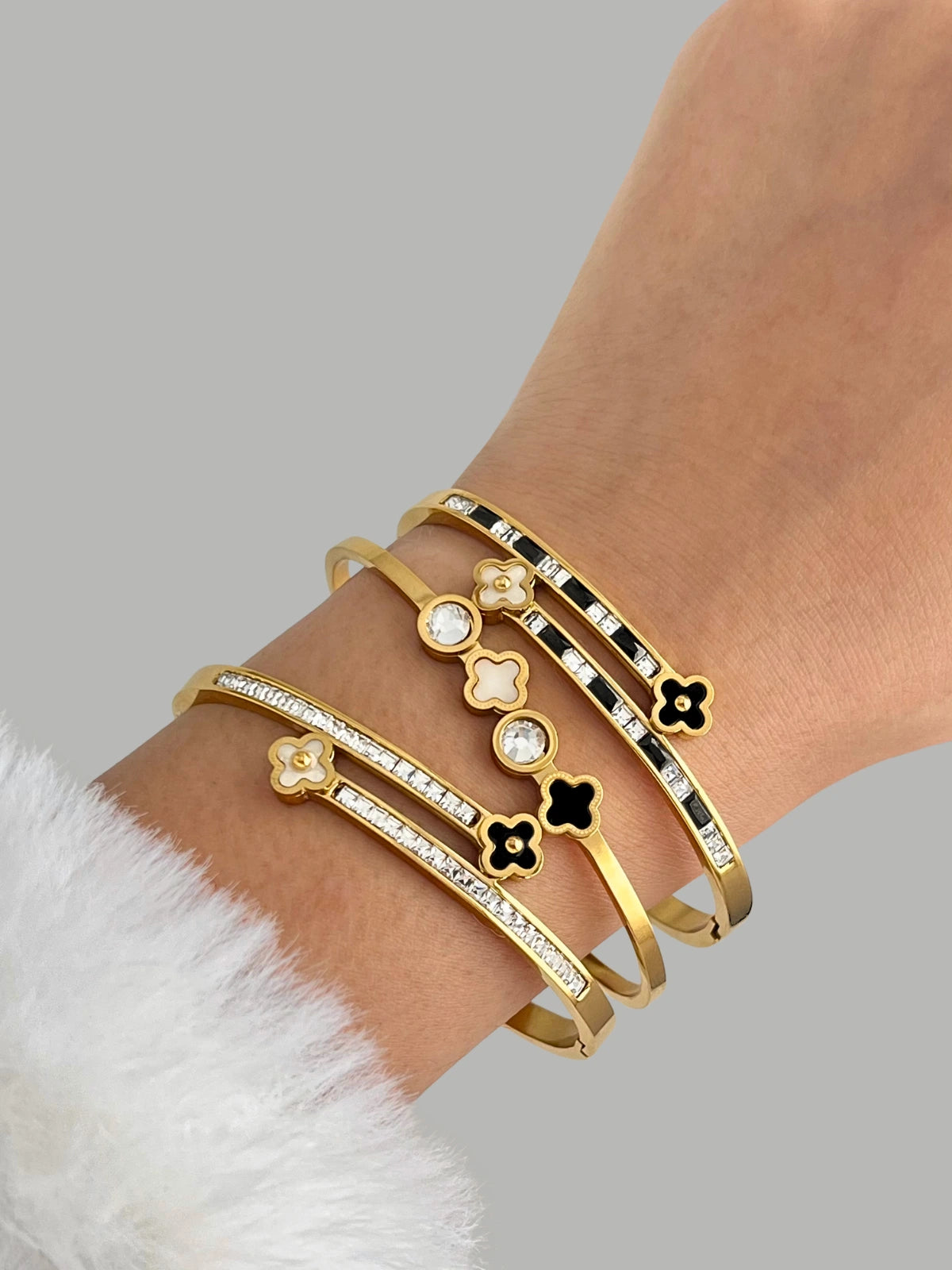 Arya Clover Bangle with floral and clover designs on a wrist against a gray background