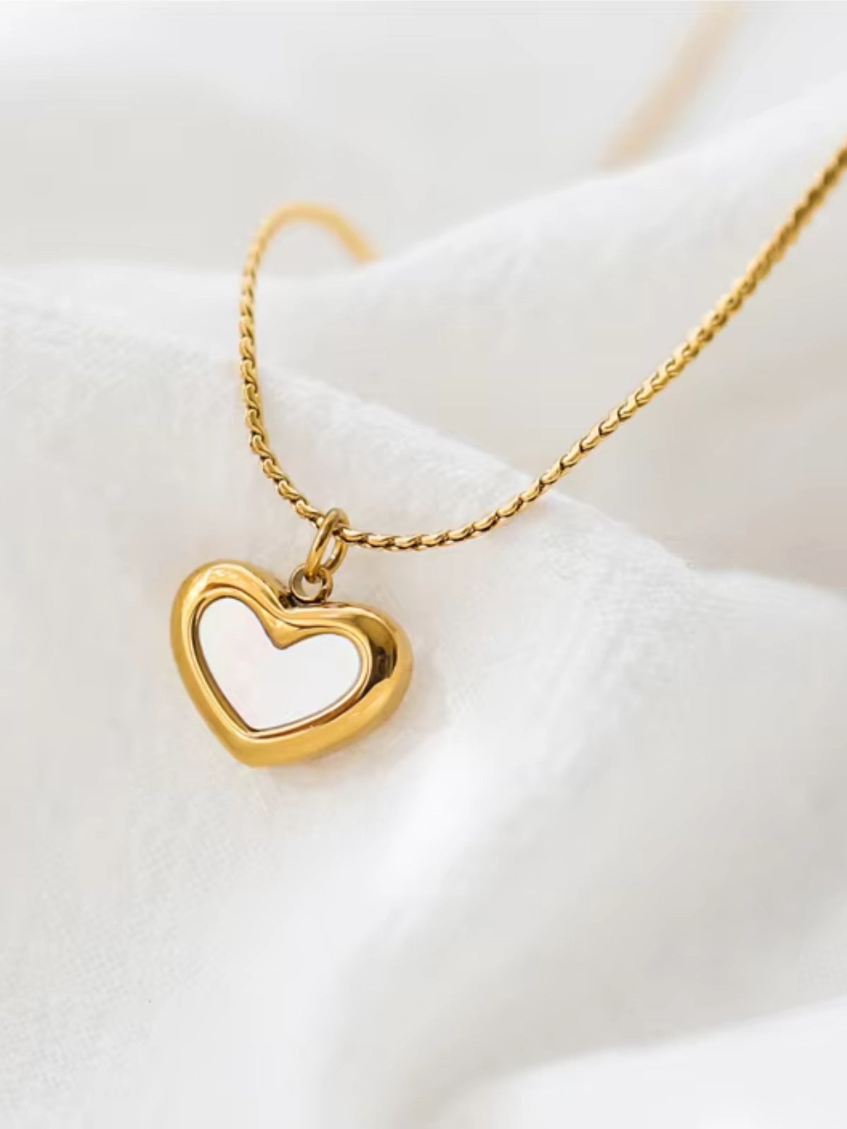 Close-up of Bella Heart Necklace by Shine With Me showing gold-plated finish, stainless steel base, heart-shaped pendant and cubic zirconia detail.