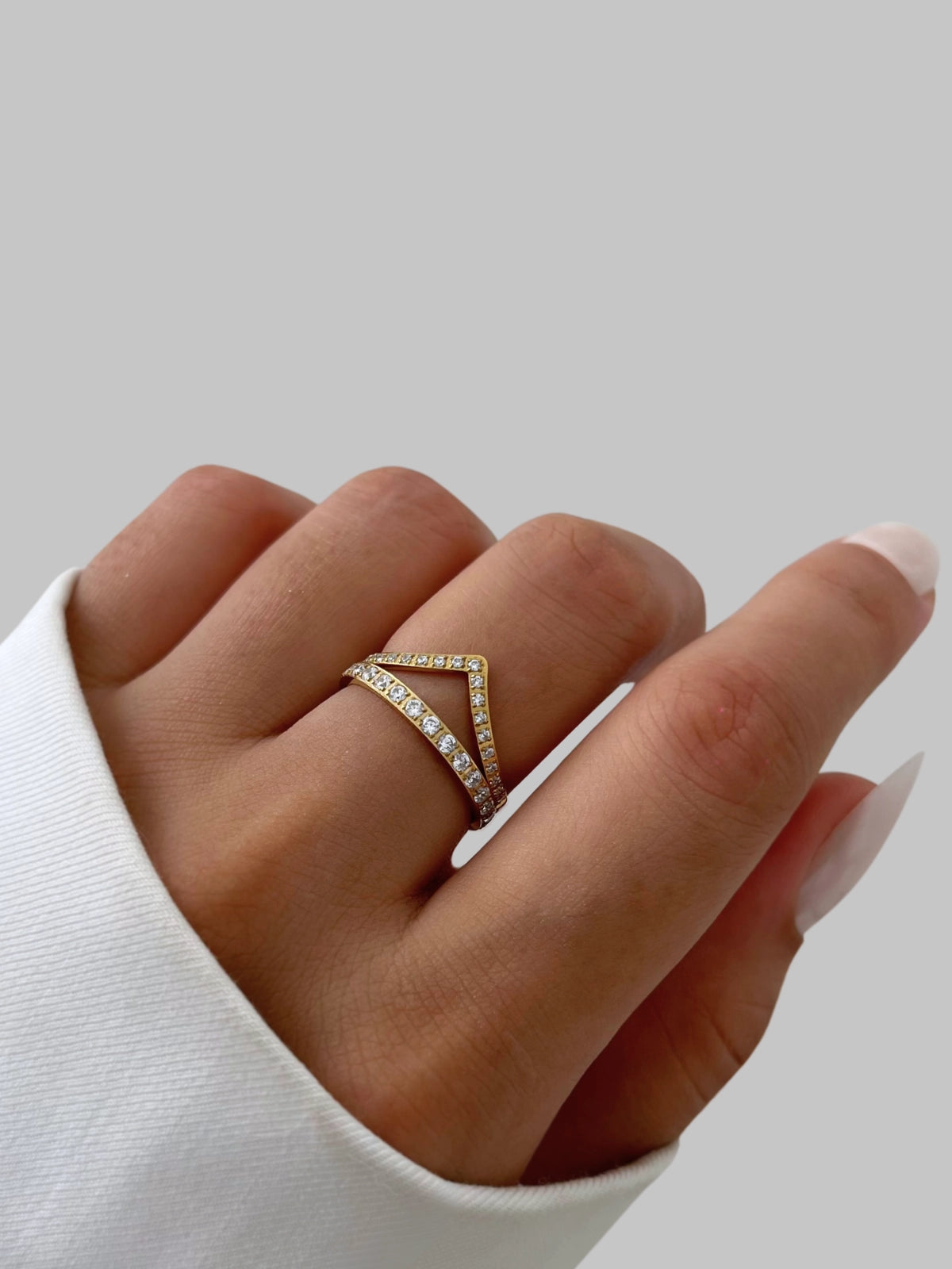Camille Ring Hand wearing a triangle-shaped diamond ring on a light gray background