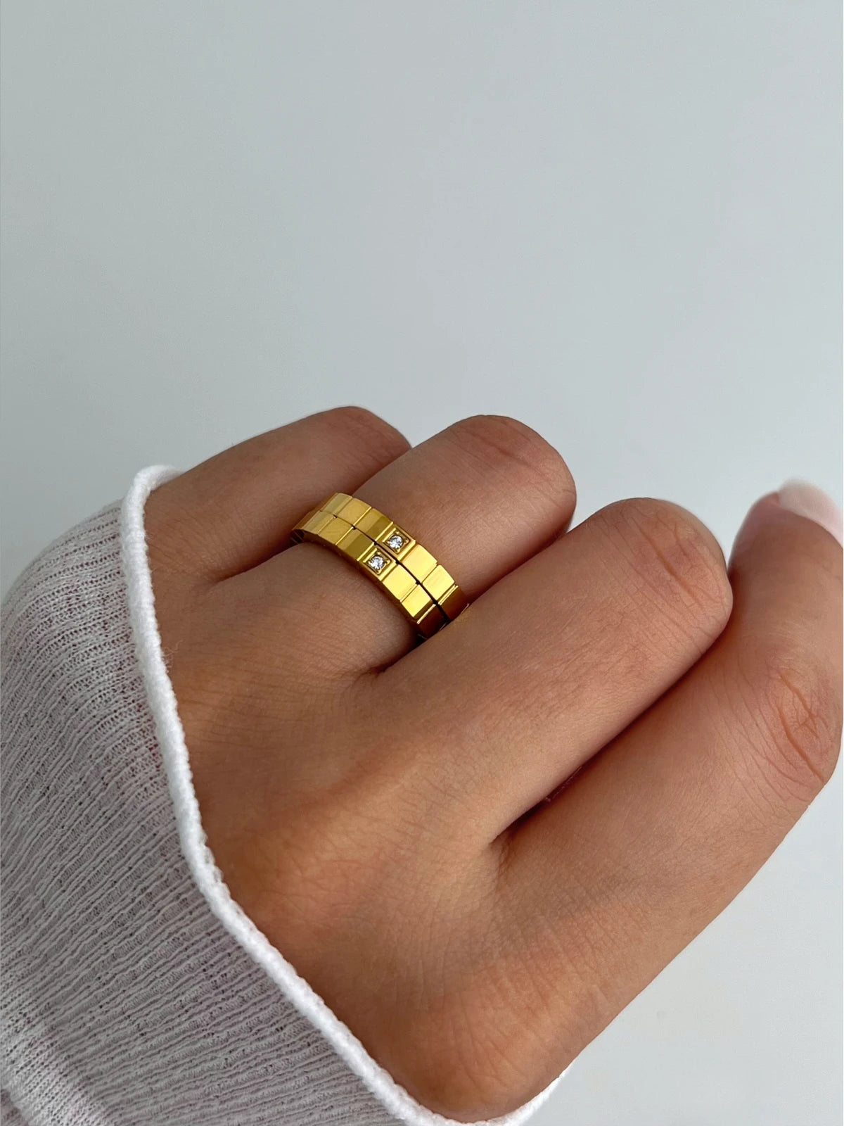 Celina RING-Gold ring on a finger with a plain background