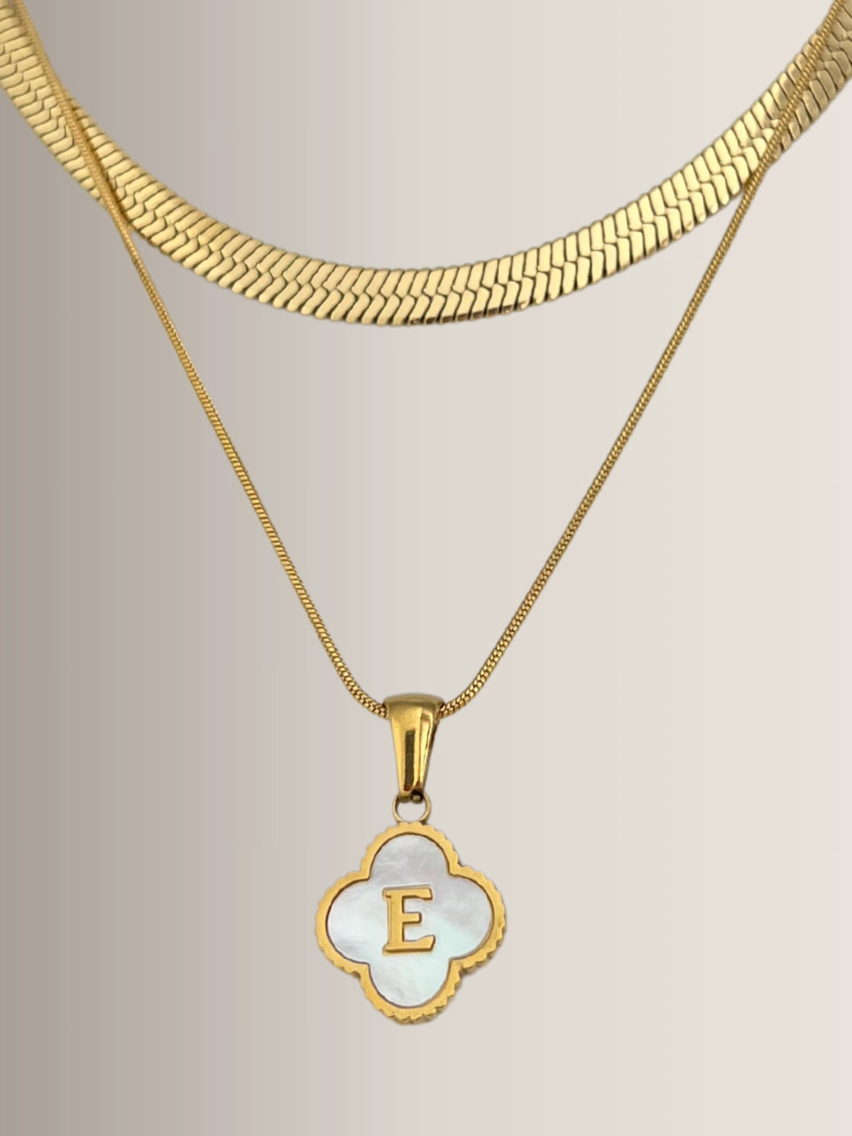 Clover Letter Necklace – Close‑Up Detail-Gold necklace with a pendant featuring the letter 'E' on a neutral background