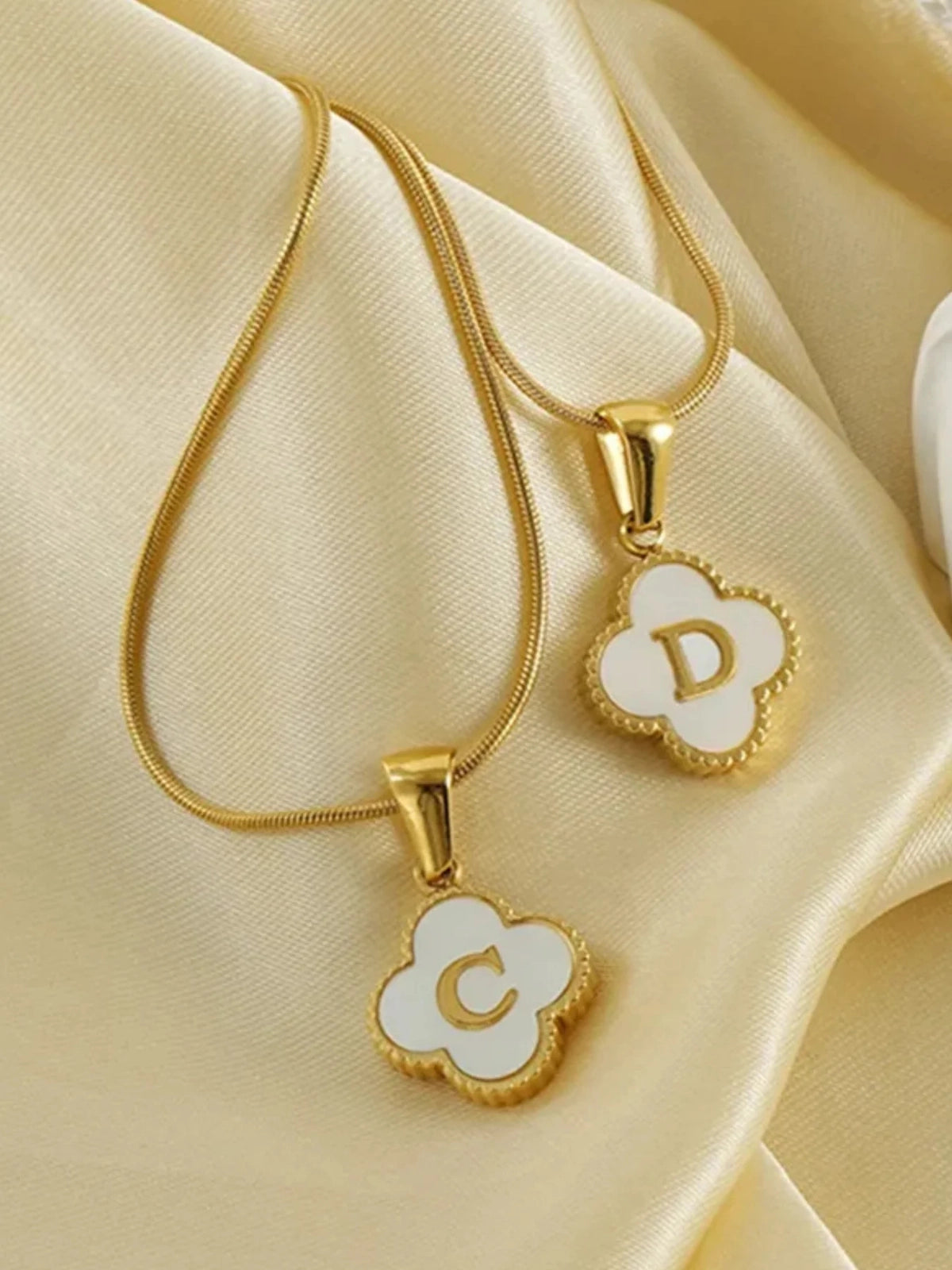Clover Letter Necklace – Close‑Up Detail-Gold necklaces with letter pendants on a beige fabric background