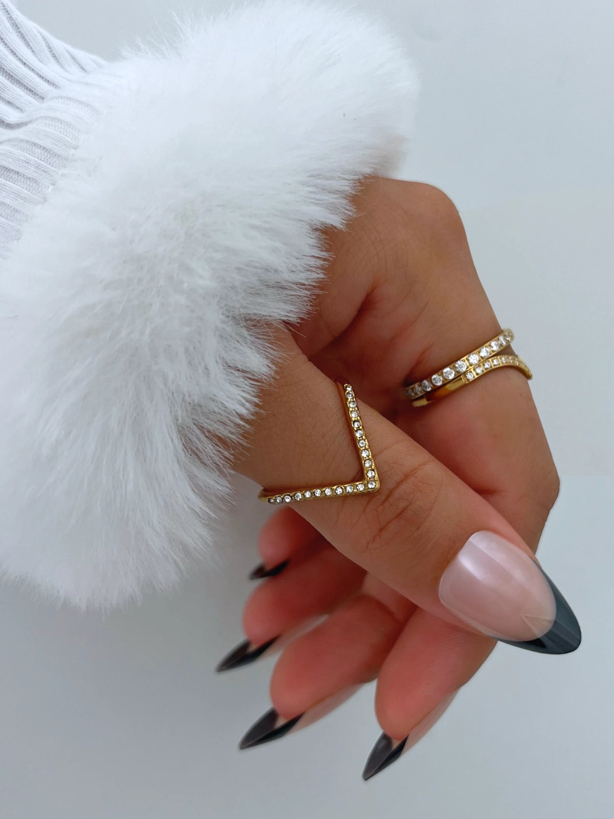 Crush Vow Ring worn on hand — 18K gold-plated stainless steel & cubic zirconia by Shine With Me-Hand wearing multiple rings with a white fluffy object in the background
