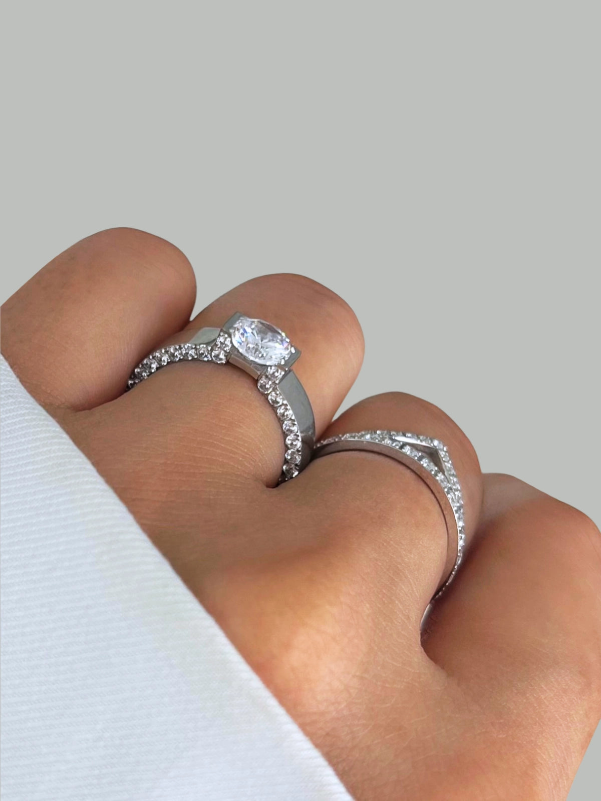 Dolores Ring – Worn on Finger-Close-up of a hand wearing two silver rings with diamond accents on a light gray background