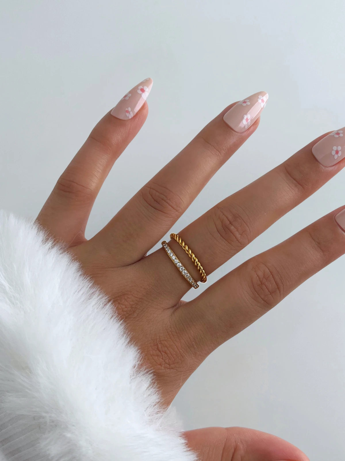 Elegance Ring – Worn on Finger-Hand wearing a gold ring with a white fur sleeve on a light background