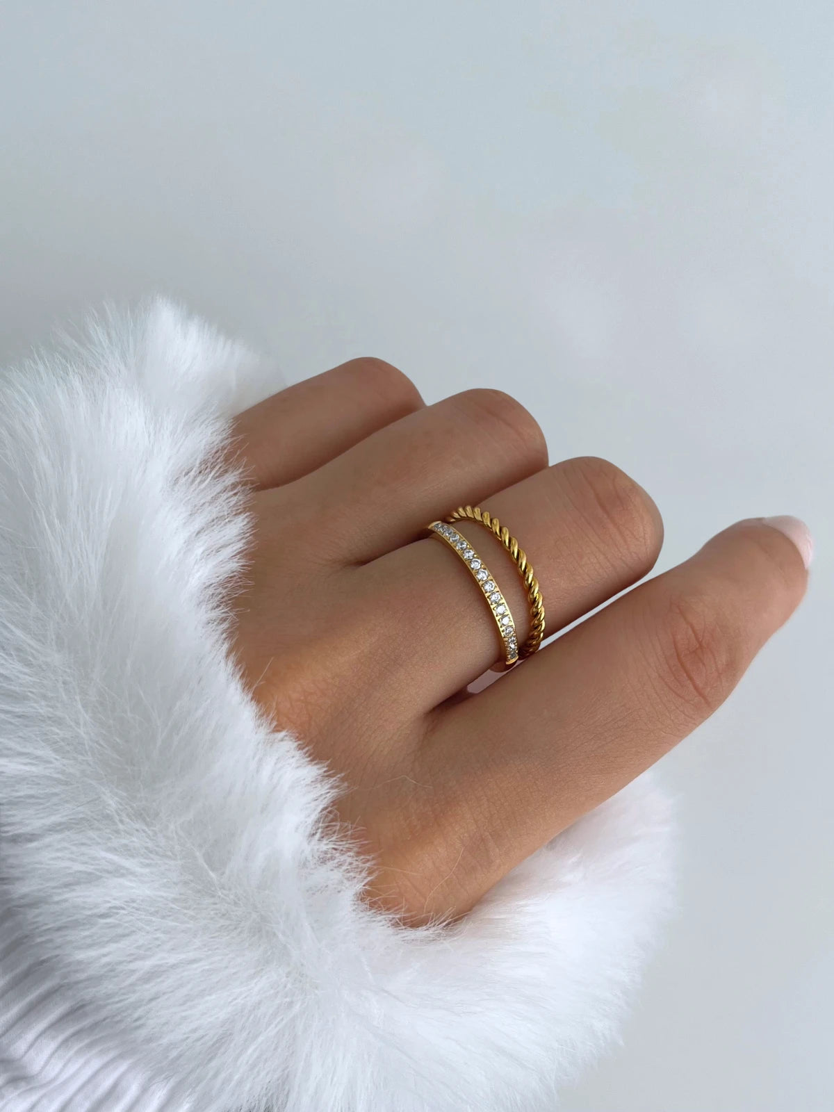 Elegance Ring – Worn on Finger-Hand wearing a gold ring on a white fur background