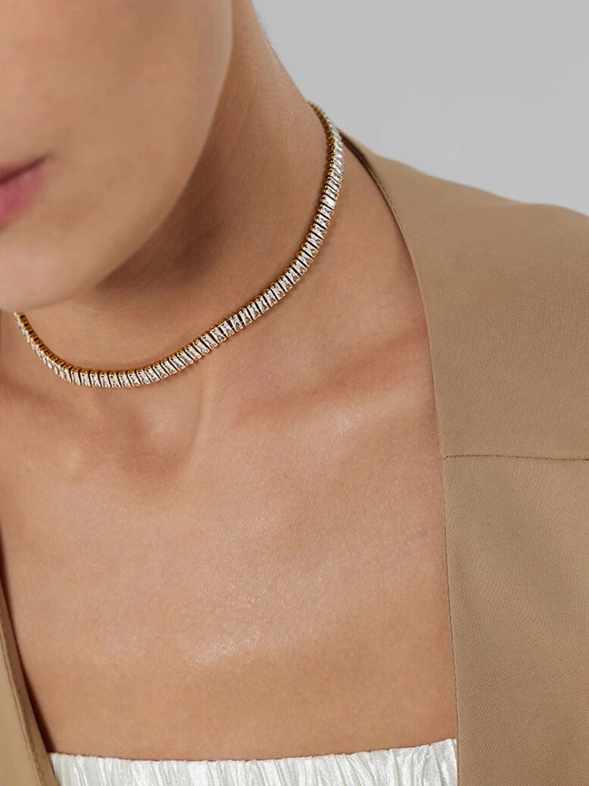 Elly_Chain Close-up of a person wearing a silver necklace with a neutral background