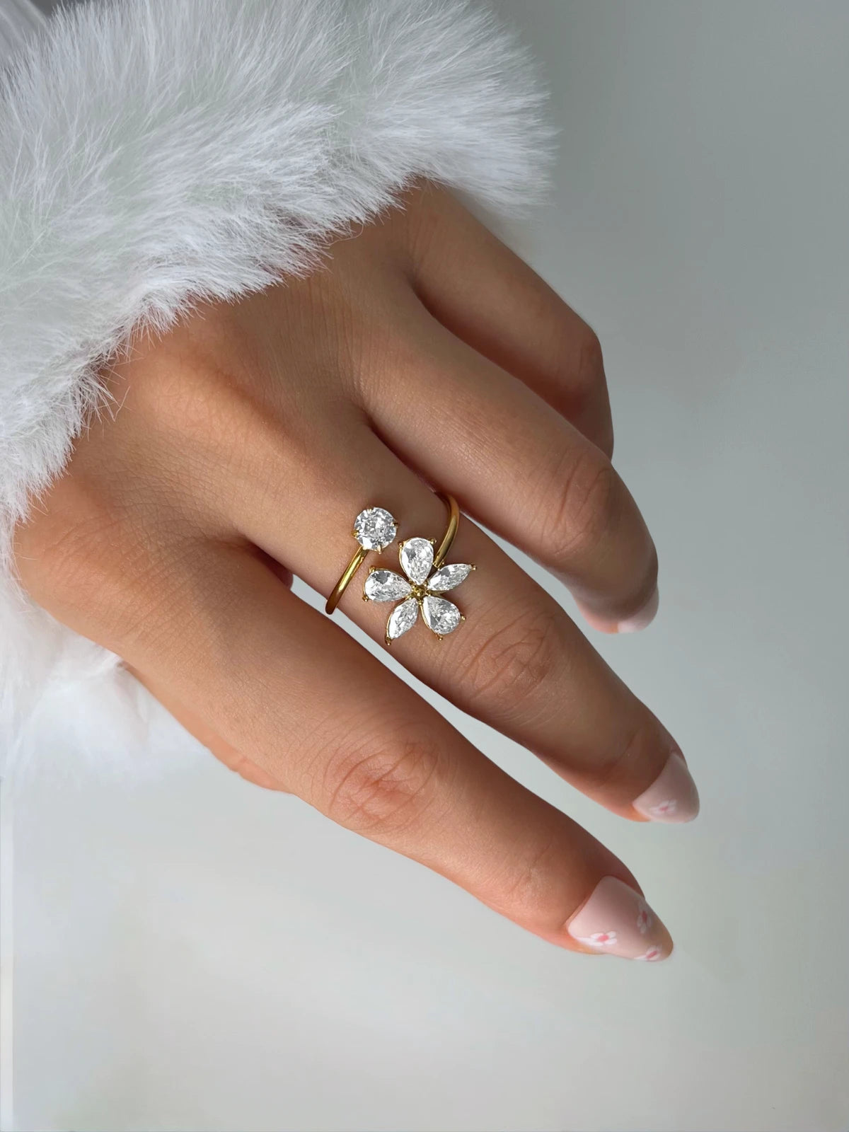 Flora Ring – Close-Up Detail-Hand wearing a decorative ring on a soft white background