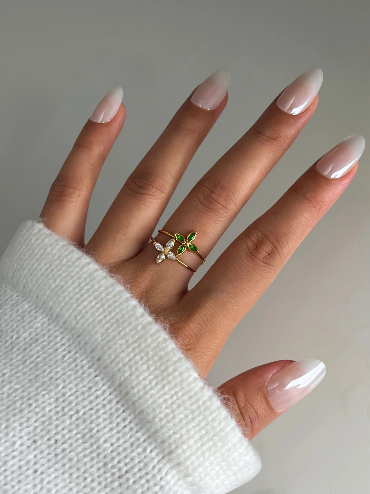 Lucia Ring 2 Hand wearing a ring with green gemstones against a neutral background SHINE WITH ME