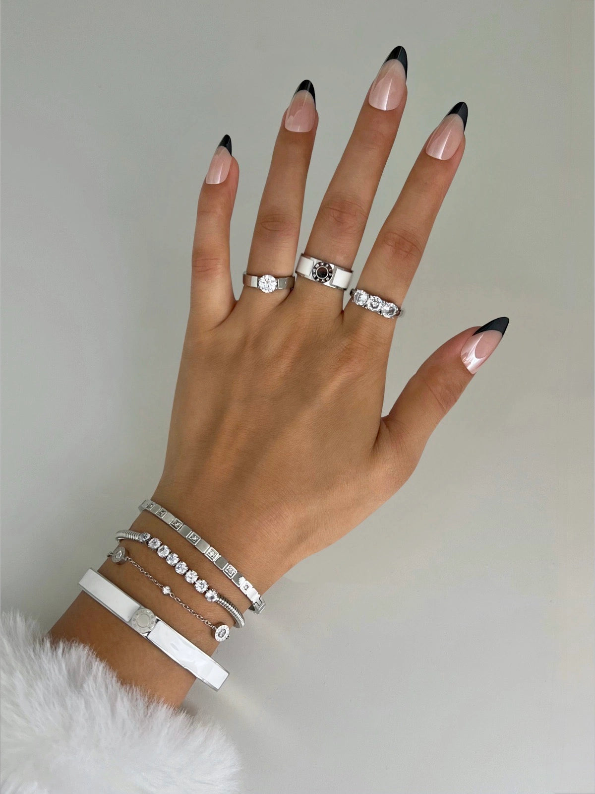 Lucia Ring – Worn on Finger-Hand wearing multiple silver rings and bracelets with black and pink nail polish on a neutral background