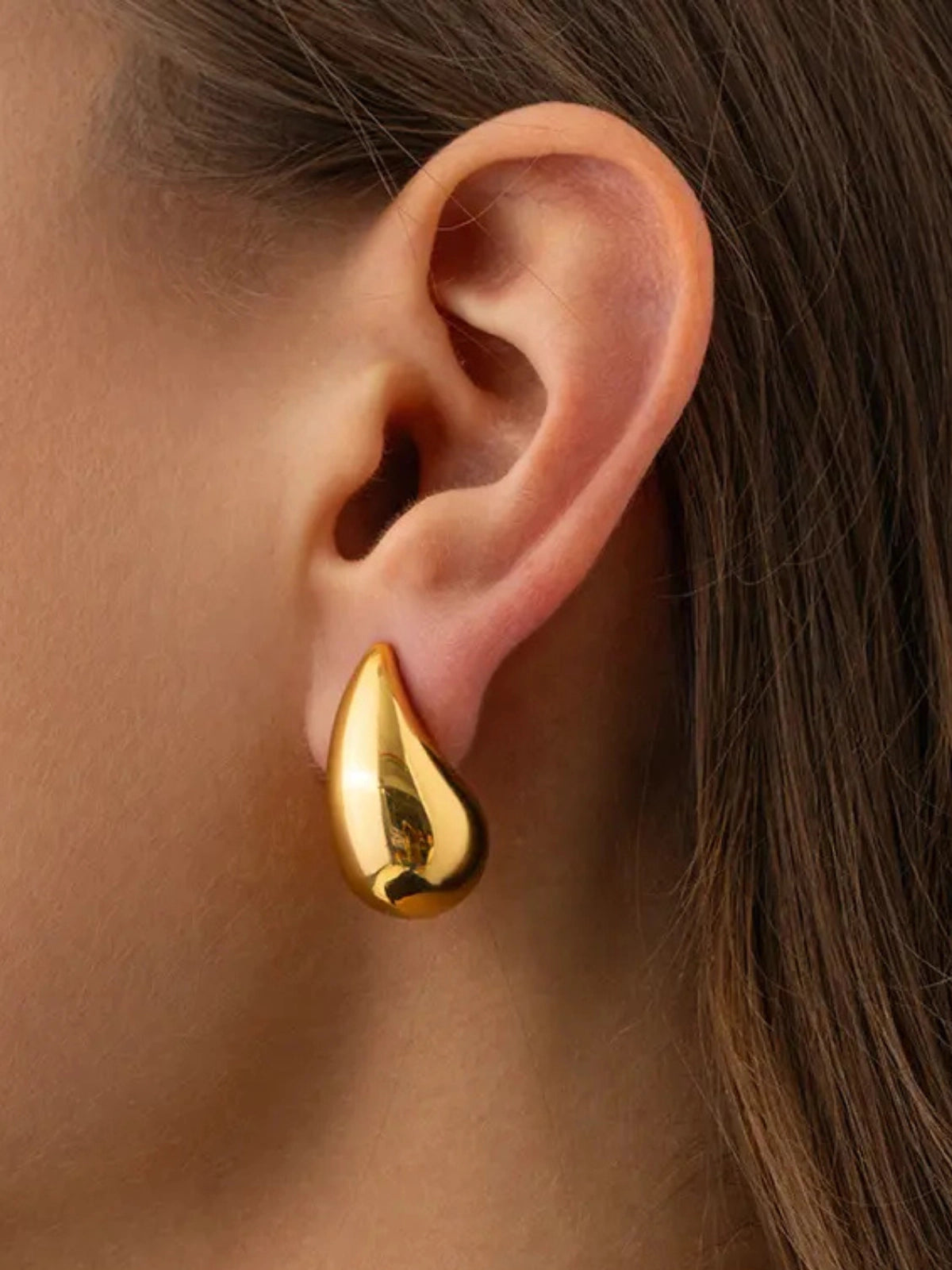 Madonna Drop Earring – On Ear Styled Shot Gold teardrop earring worn on an ear with a blurred background
