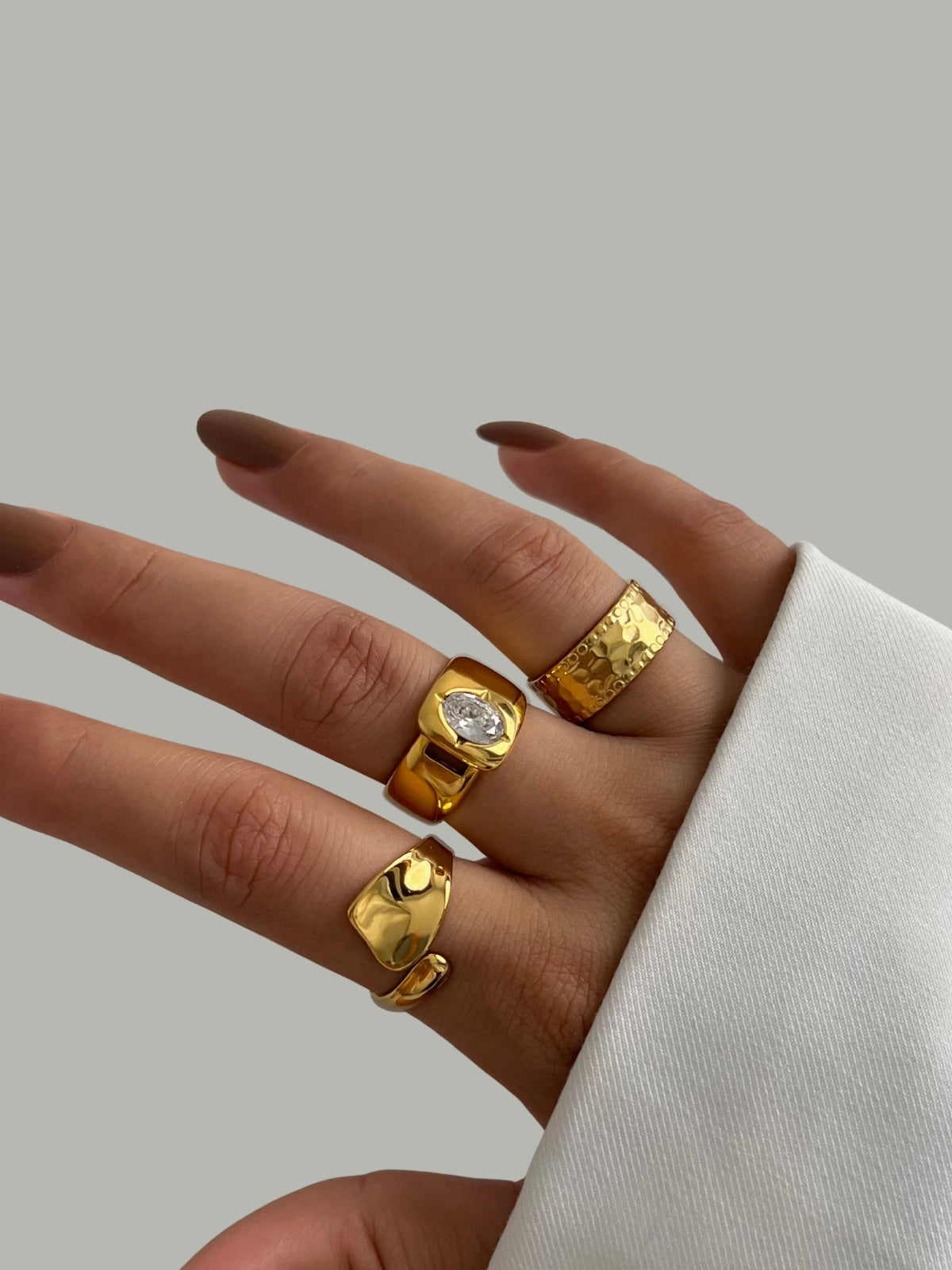 Majesty RING Hand wearing three gold rings on a neutral background