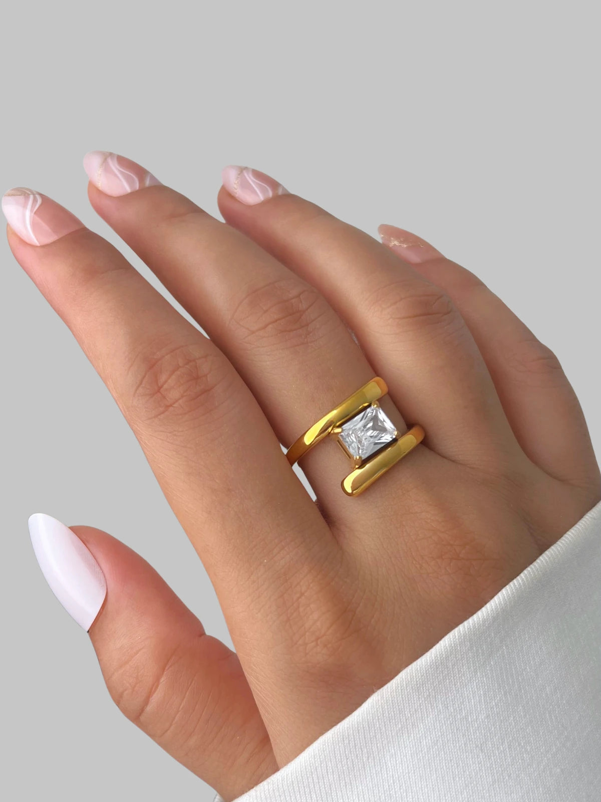 Moonbeam Ring – Lifestyle Look-Gold ring with a diamond on a hand against a gray background