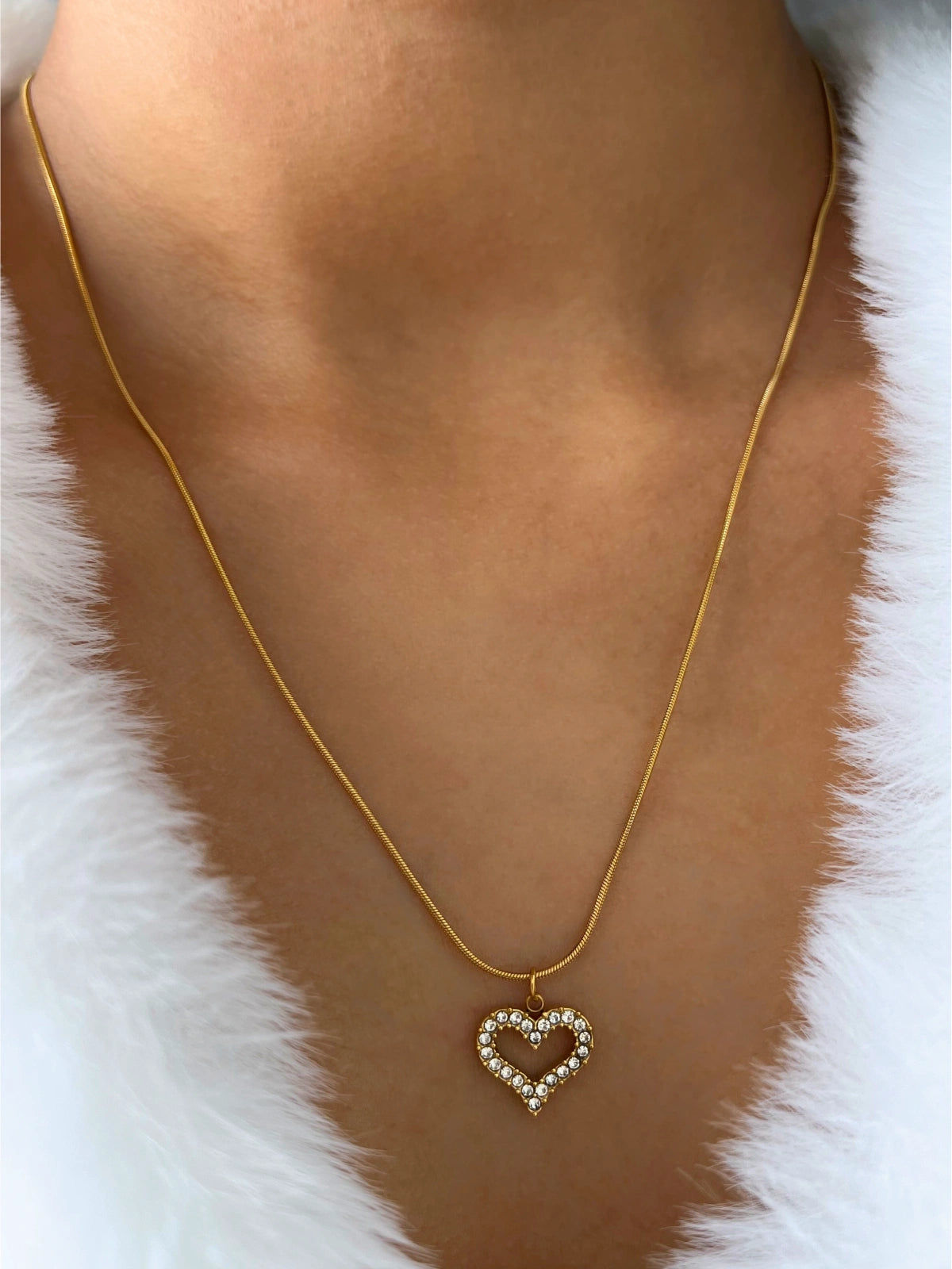 My Whole Heart Necklace – On Model-Gold necklace with a heart-shaped pendant on a white fur background