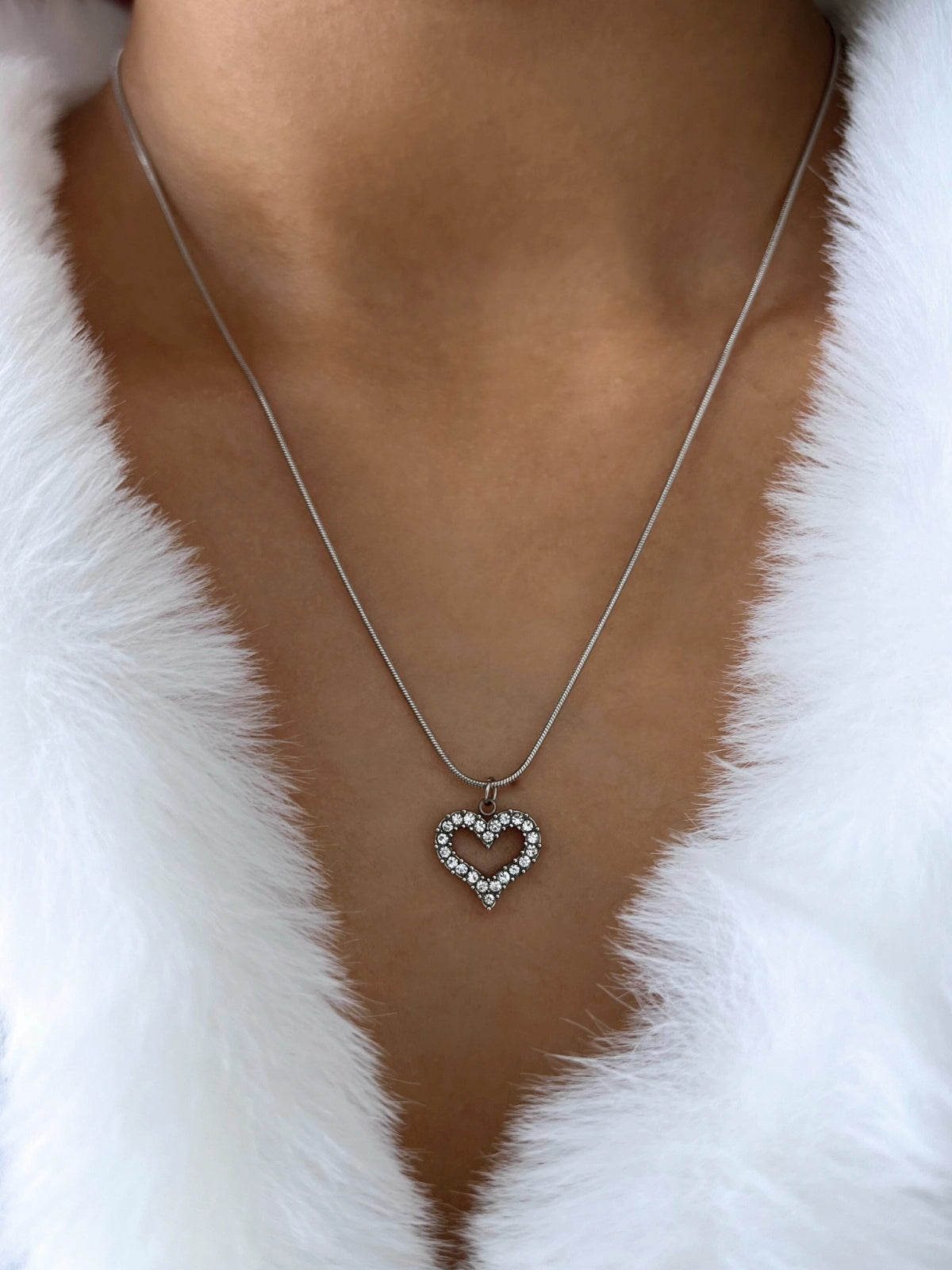 My Whole Heart Necklace – On Model-Heart-shaped necklace with a pendant on a person wearing a white fur garment.