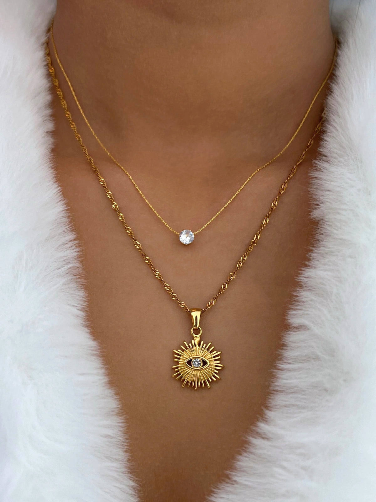 Rawah Necklace & RING-Gold necklace with a sun-shaped pendant on a white fur background