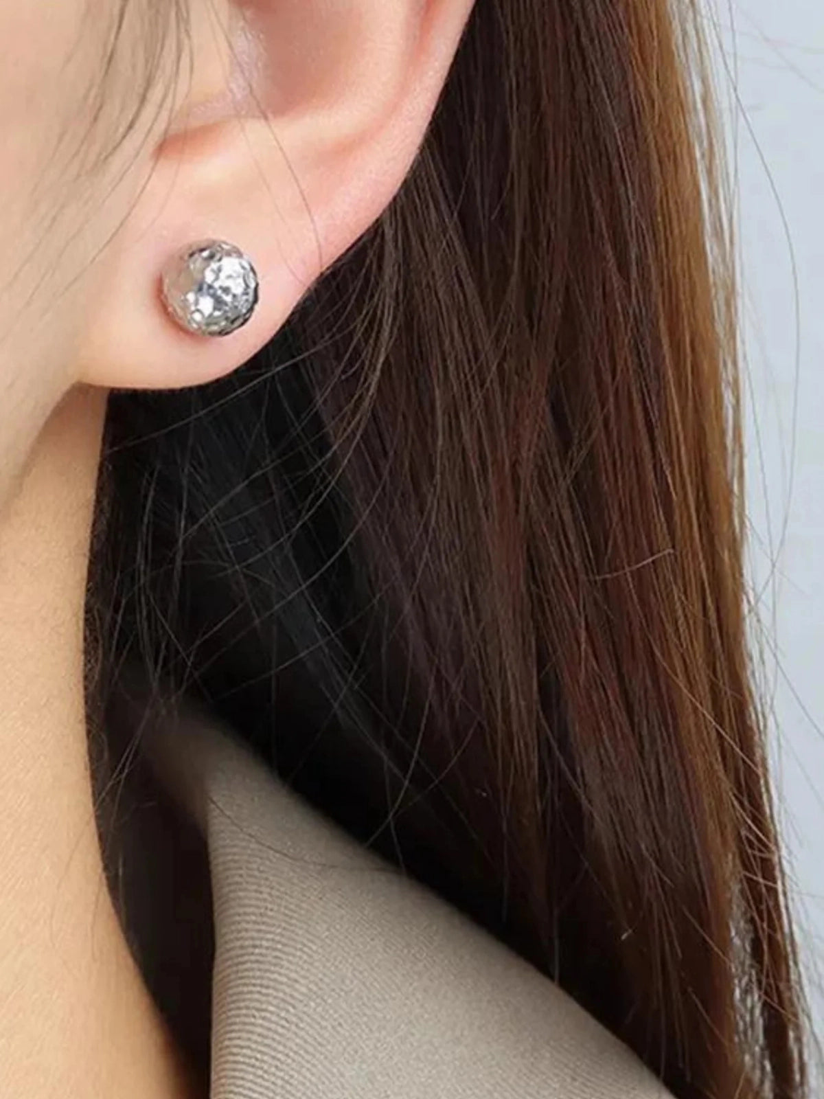 Raya Stud Earring – On Ear Styled Shot-Close-up of a person wearing a silver stud earring with a clear gemstone.