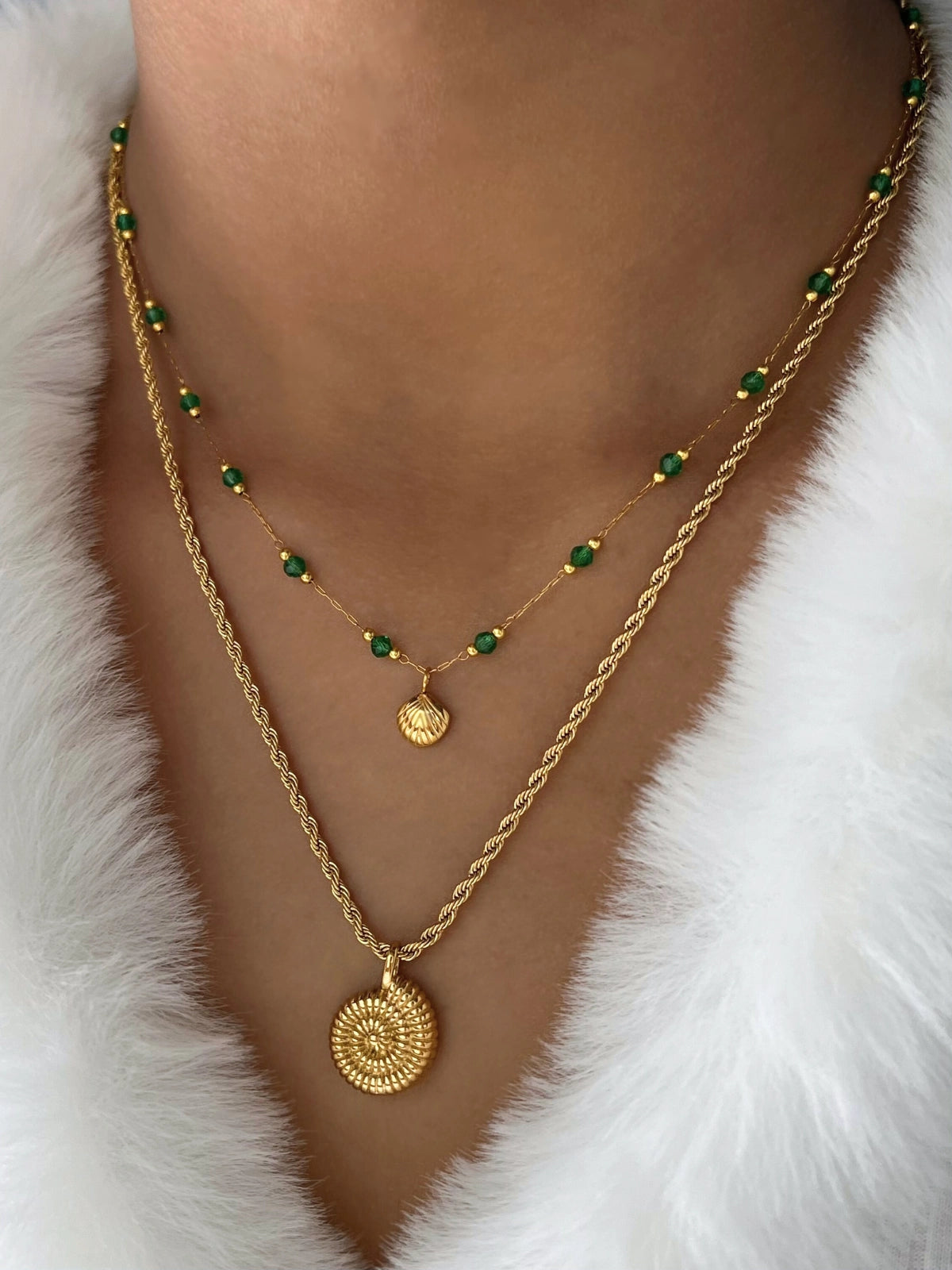 Shell Bloom Necklace – Close‐Up Detail-Gold necklaces with green beads on a white fur background