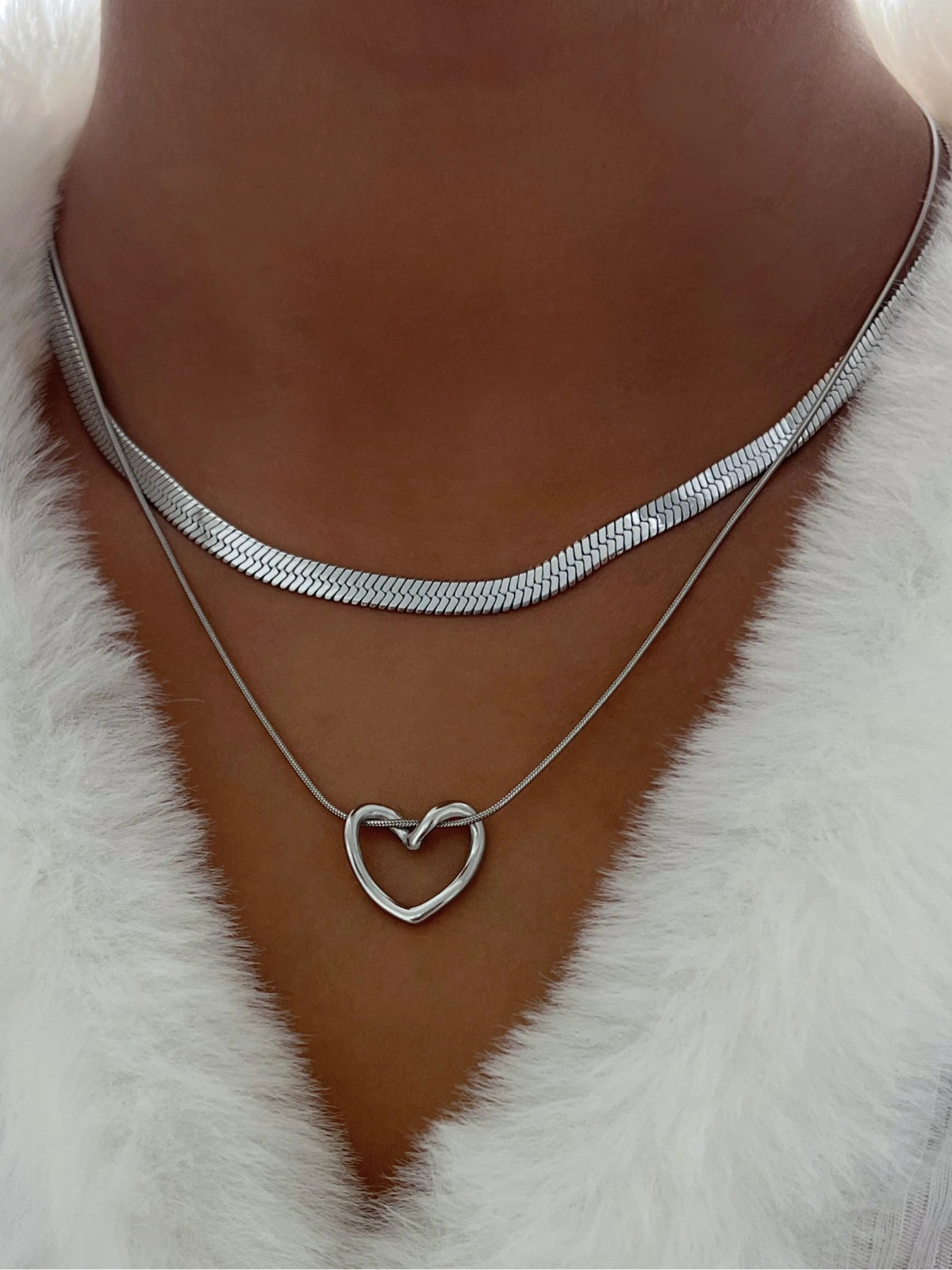 Slinka Chain – On Model Styled Shot-Silver heart-shaped necklace on a person wearing a white fur garment.