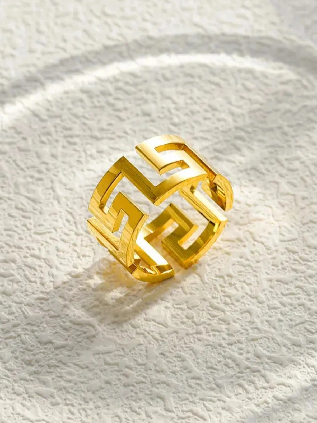 Soulband Ring – Detail-Gold geometric ring on a textured white surface