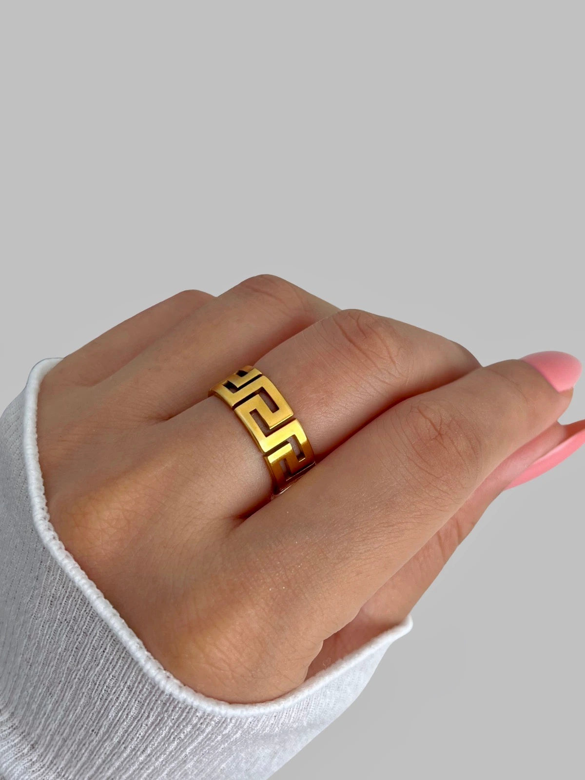 Soulband Ring – Worn on Finger-Gold ring on a person's finger against a gray background