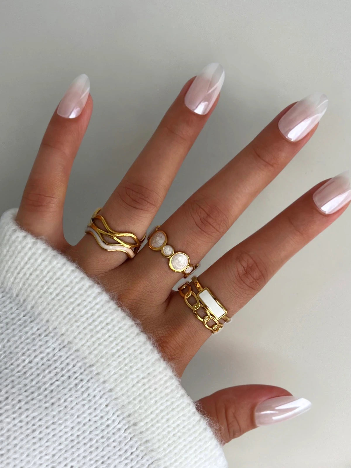Sozi RINGS Hand wearing gold rings with a plain background