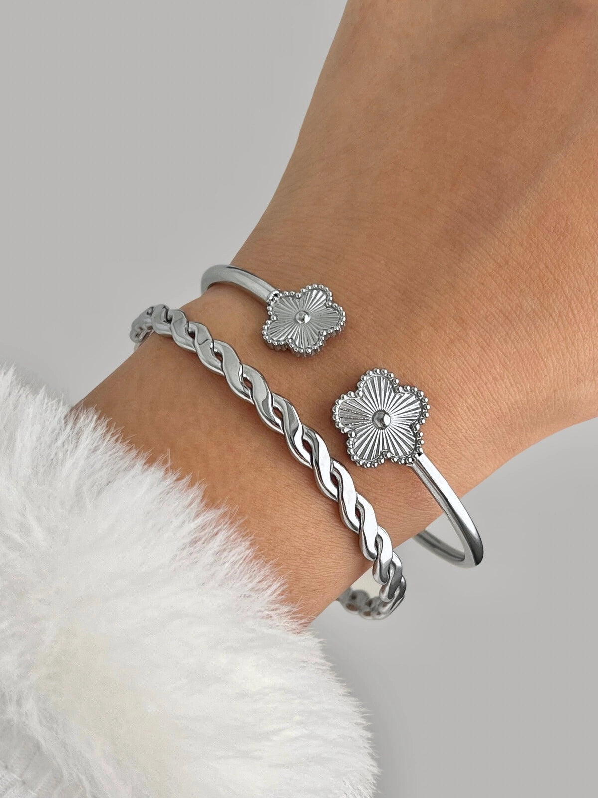 Sunveil Bangle Silver bracelet with floral designs on a wrist against a gray background