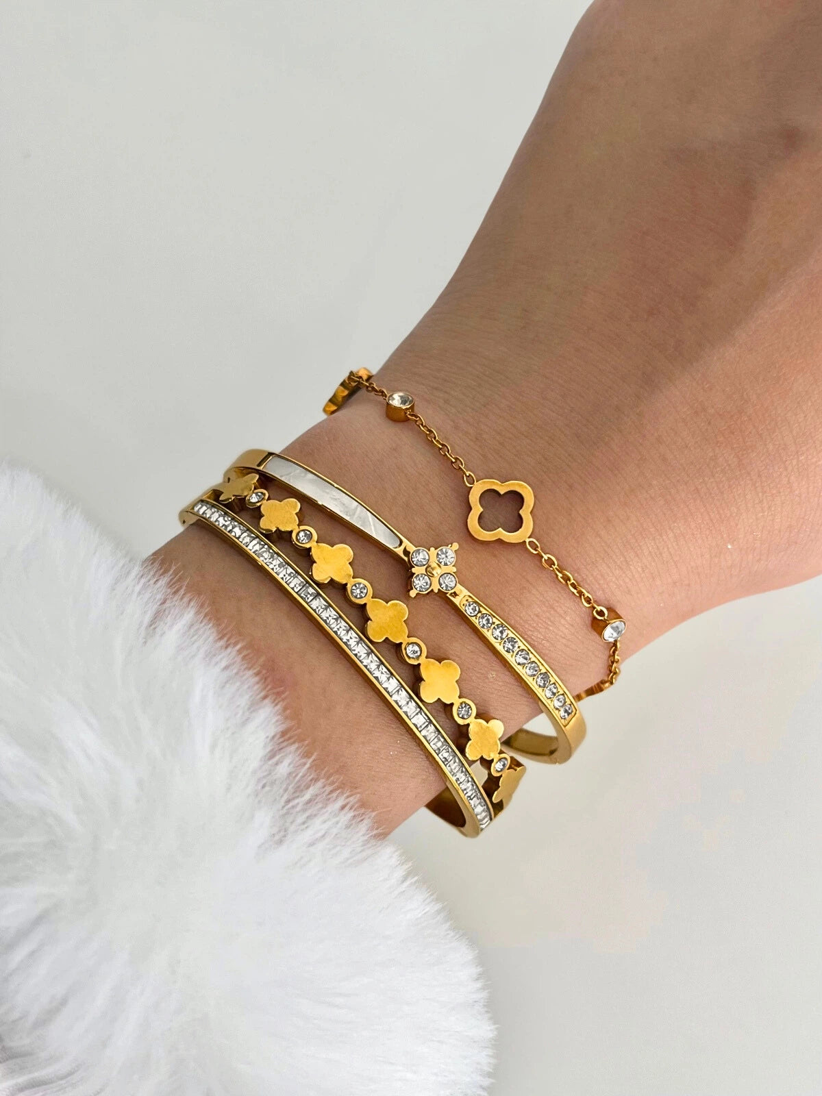 Twilight Clover Bangle –Gold bracelet with clover designs on a wrist against a white background