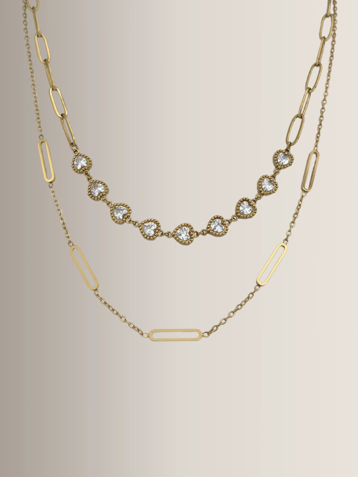 Velina Heart Necklace – Close‑Up Detail-Gold necklace with diamond accents on a beige background