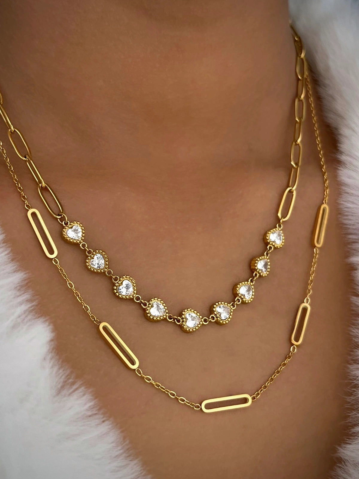 Velina Heart Necklace – On Model Styled Shot-Gold necklace with clear stones on a person wearing a fur coat.