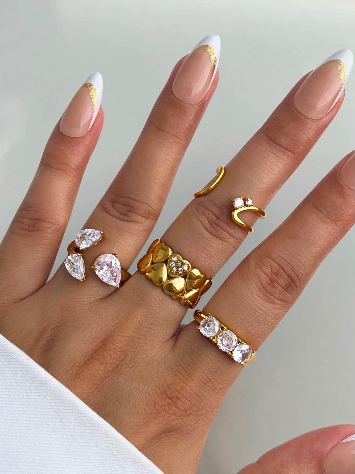 Victoria Ring – Close‑Up Detail-Hand wearing multiple gold and diamond rings on a neutral background
