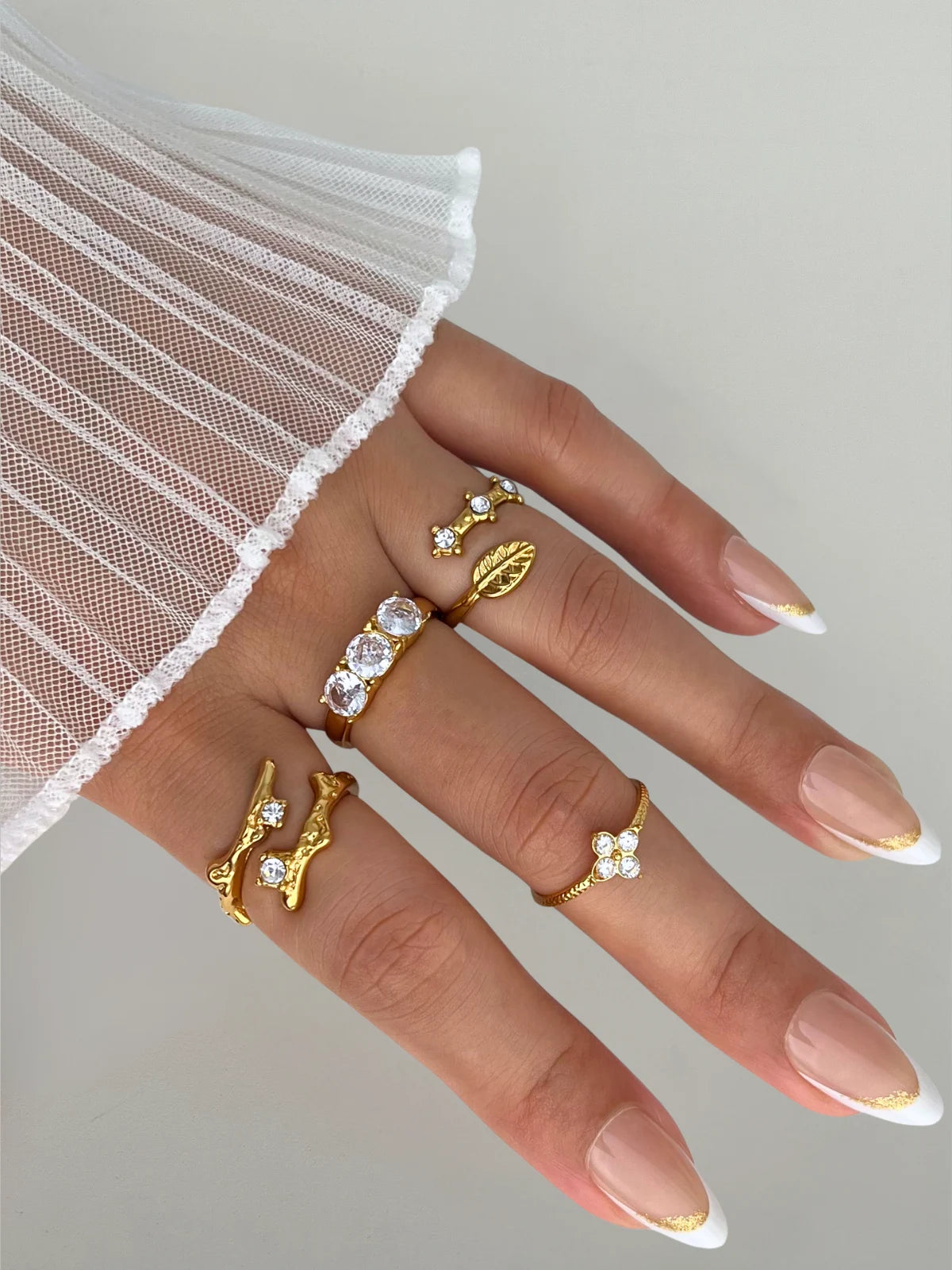 Victoria Ring – Material & Design Highlight-Hand wearing multiple gold and crystal rings on a neutral background