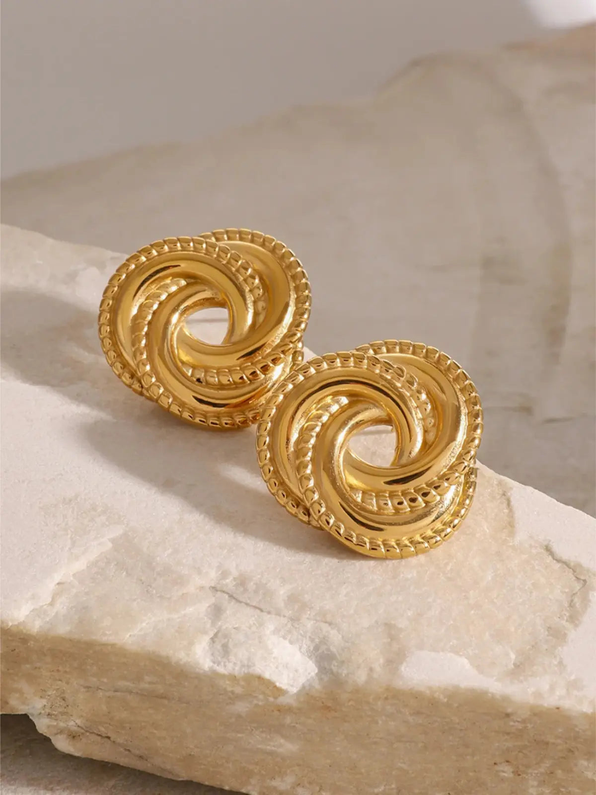 Close-up of Vintage Earrings by Shine With Me showing the gold-plated finish, fine craftsmanship and vintage-inspired design. Gold spiral earrings on a textured stone surface