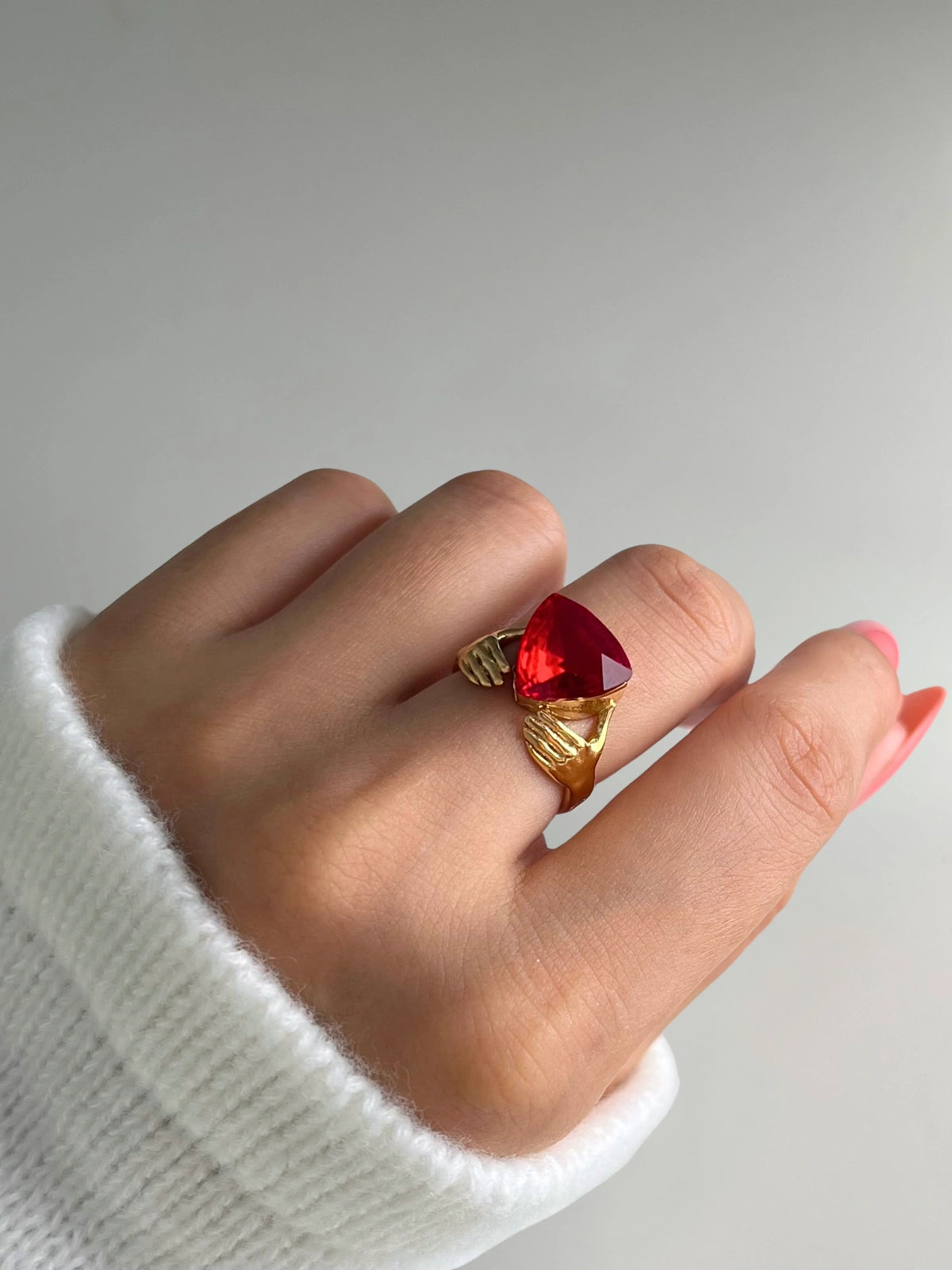 Vivienne Ring – On Model Styled Shot-Hand wearing a gold ring with a red gemstone on a neutral background