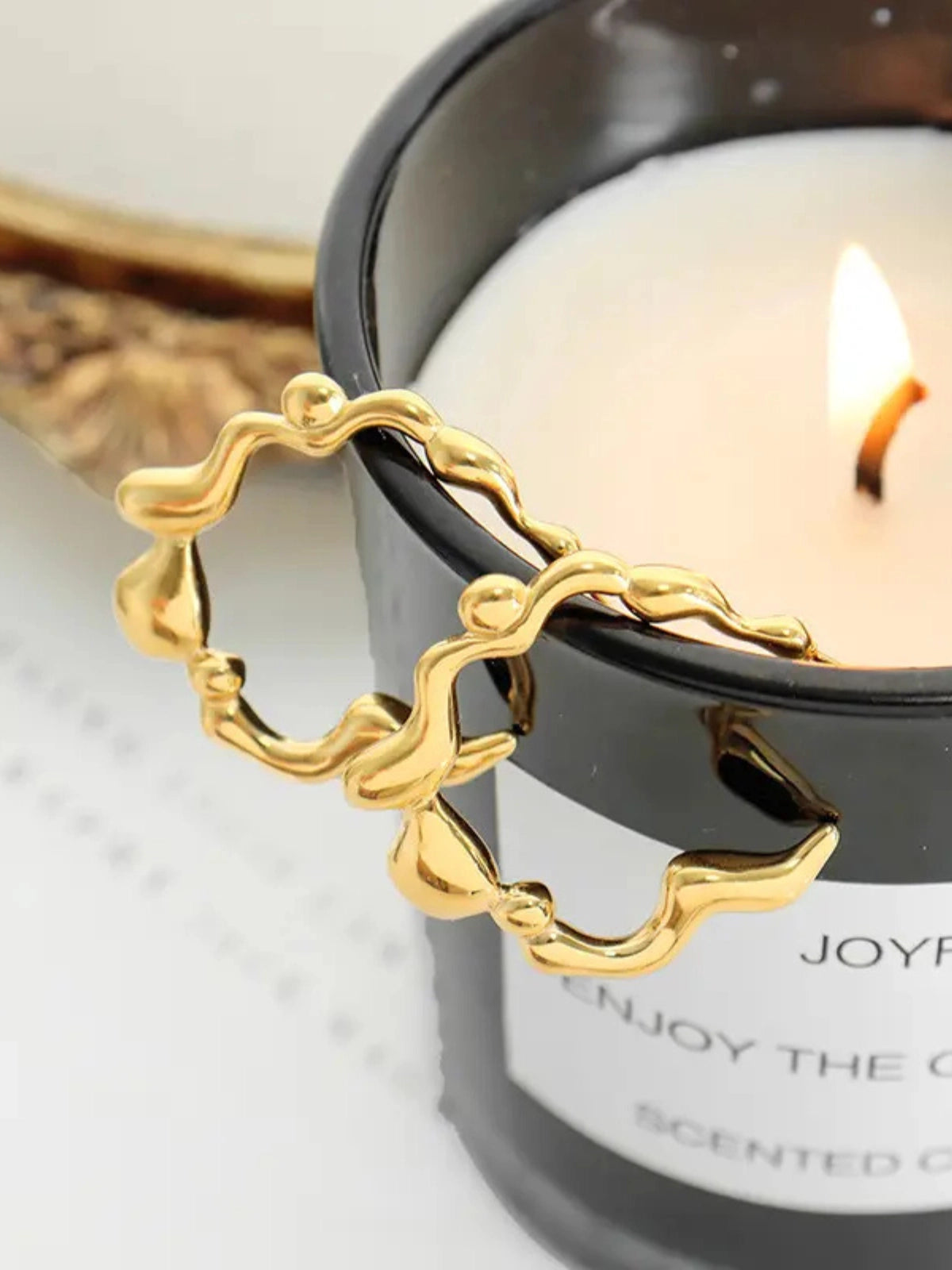 Close‑up of Zelina Earrings by Shine With Me showing the gold‑plated finish, stainless steel base and fine craftsmanship- Gold candle snuffer in front of a lit candle.