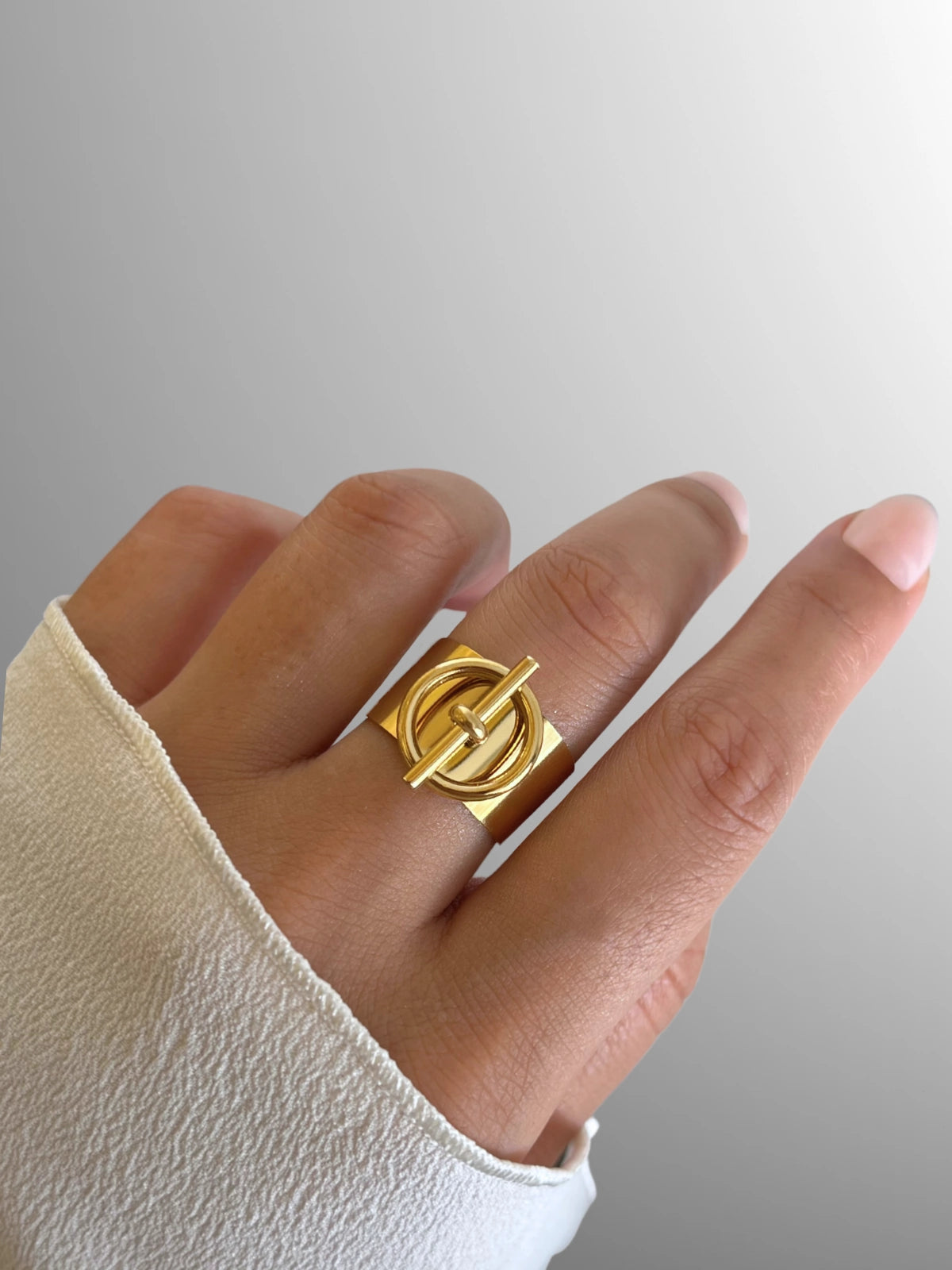 dorian-belt-ring-closeup-detail-shine-with-me. Gold ring on a hand with a plain background