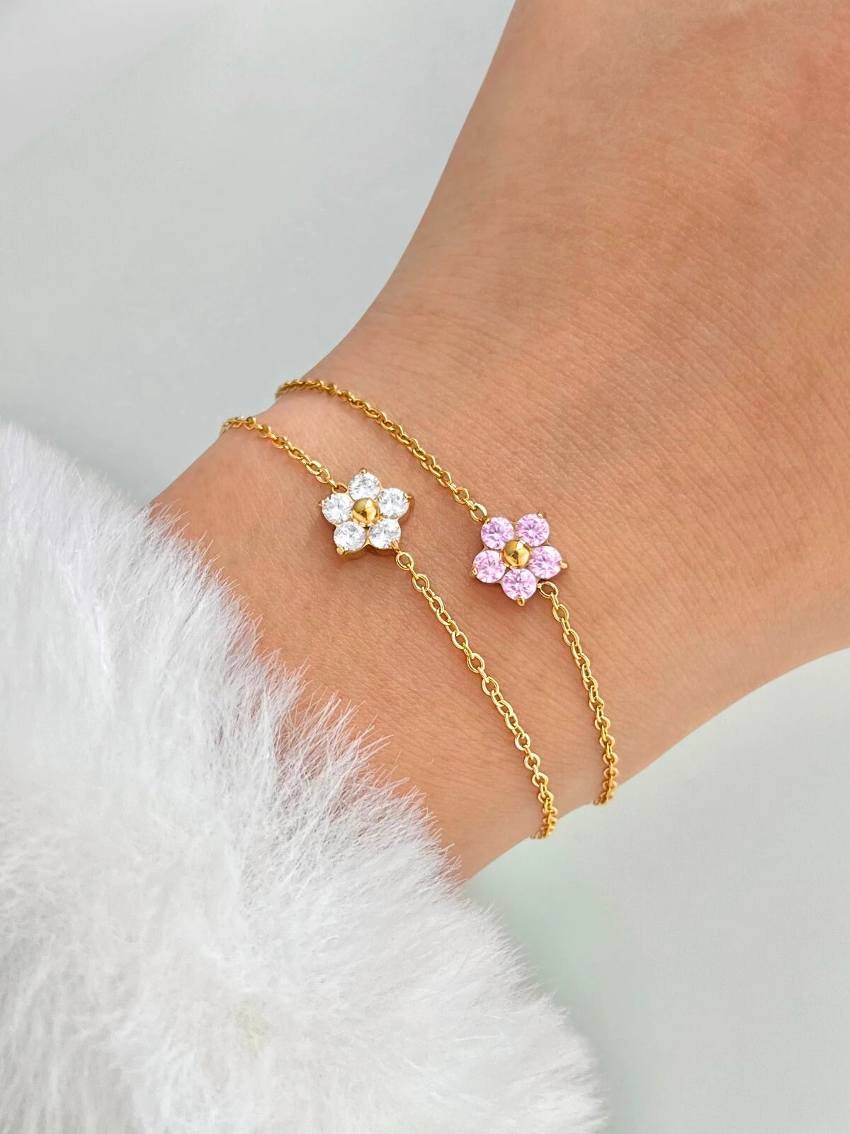 Close-up of Hannah Bracelet showing refined gold bracelet design. Gold flower anklets on a person's ankle against a light background