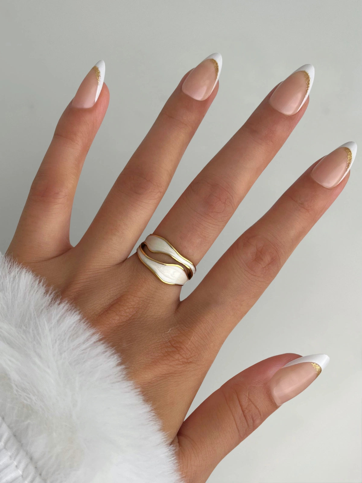 luxe-spiral-ring-closeup-detail-shine-with-me Hand wearing a gold ring with a neutral background